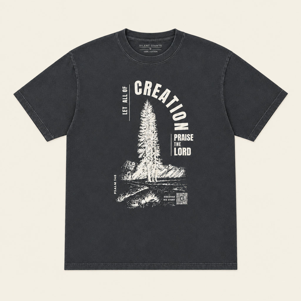 A dark charcoal gray graphic t-shirt laid flat on an ivory background. The shirt features a white distressed graphic of a pine tree with the text 'CREATION' arched above and 'PROVIDE FOR THE LORD' below.