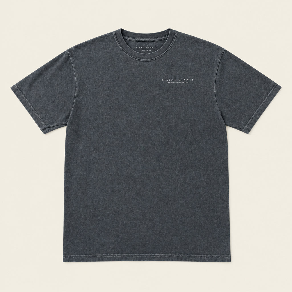 A dark gray crewneck t-shirt with 'Silent Giants above He Speaks through you.' printed in small white text on the left chest, laid flat on an ivory background.